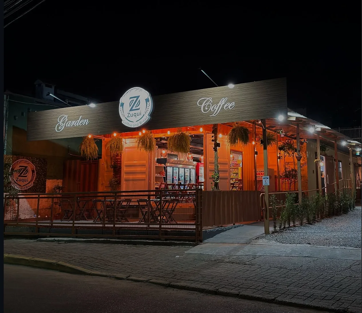 Fachada iluminada do Zuqui Garden Coffee no Canto da Praia
